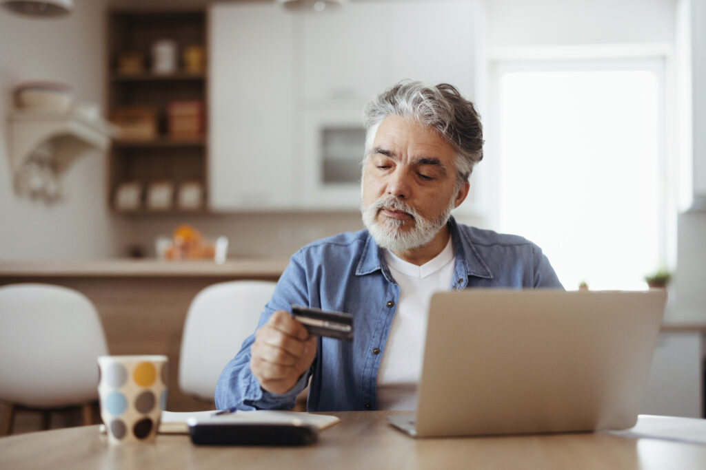 Mature man sing credit card at home